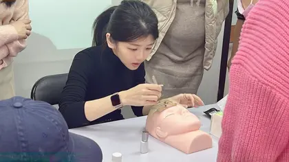 美睫老師在假人頭上示範接睫毛手法